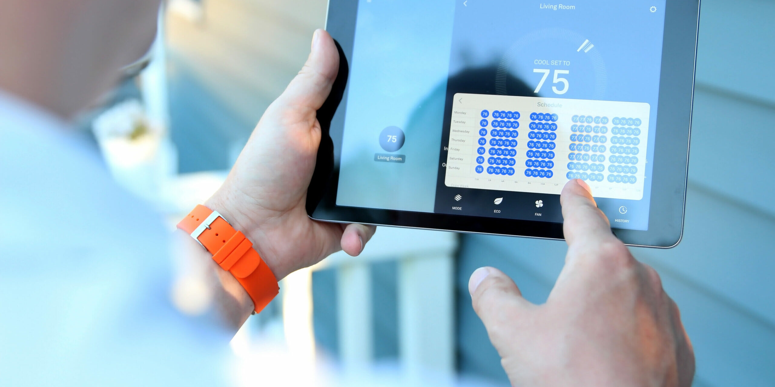 Man is Adjusting a temperature using a tablet with smart home app