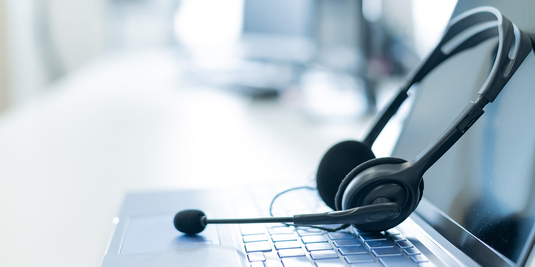 Call center operator desktop. Close-up of a headset on a laptop. Help desk. Workplace of a support service employee. Headphones with a microphone for voip on a computer keyboard